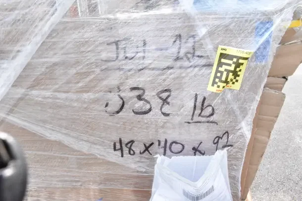 Pallet wrapped with clear plastic, marked "JUL-12," weighs 338 lbs, dimensions 48x40x92; includes new scratch and dent items.