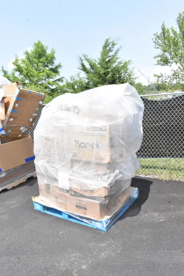 Stack of 29 brand new scratch and dent items on a pallet, wrapped in plastic. Includes plates, forks, cups, and containers.