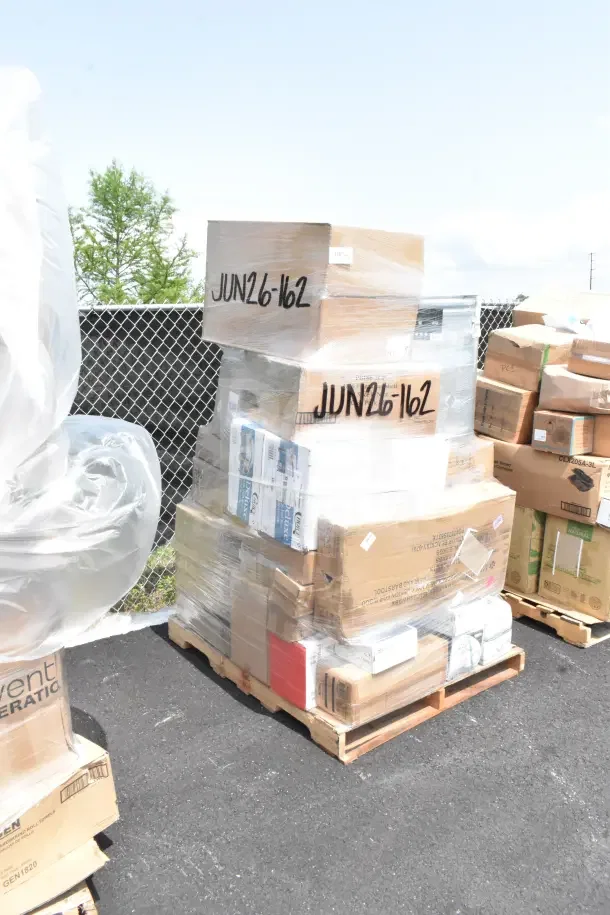 Stacked pallets of assorted kitchen items including plates, speed rail, glasses, in original boxes, marked "JUN26-162".
