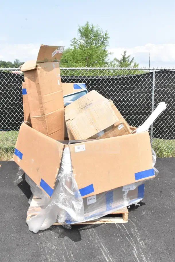 Large cardboard box on a pallet containing 18 scratch and dent items including a trash can, drying rack, steam table.