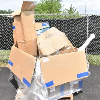 Large cardboard box on a pallet containing 18 scratch and dent items including a trash can, drying rack, steam table.