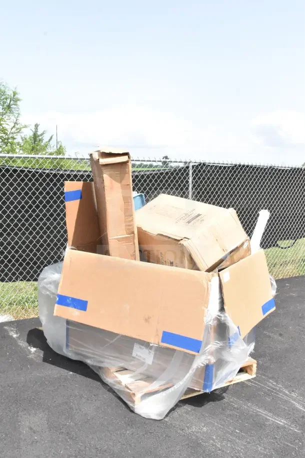 Cardboard box with wrapped items labeled for auction, including a trash can, drying rack, and steam table, showing signs of wear.