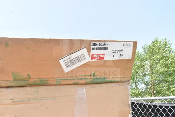 Cardboard box labeled "Metro," model XTR2448XEA, containing pan drying rack with visible scratches and dents.