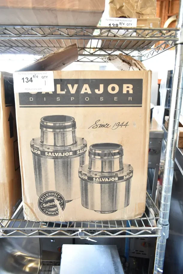 Cardboard box of Salvajor disposer, marked "Since 1944," on metal shelving. Auction label "134" visible.