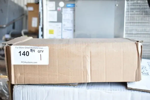 Cardboard box labeled "140 QTY 1" from PCI Auctions, containing Watts LFN250B-Z2-020 Iron Body Water Pressure Regulator.