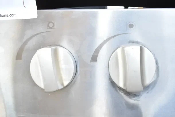 Close-up of two control knobs on a Cooking Performance Group Commercial Single Burner Gas Stock Pot Range, showing minor scratches.