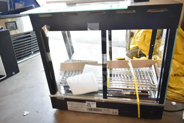 Brand new Avantco 177HDC26 heated display case, 26" countertop, 3 shelves, sliding doors, 120V, with visible packaging.
