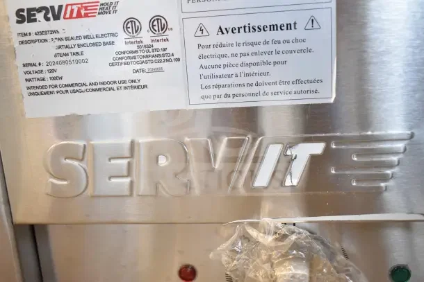 Alt text: "2024 ServIt 423EST2WS electric steam table, two pan sealed well, brand label and safety warnings visible, 120V, 1 phase."