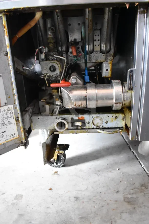 Pitco Frialator commercial gas 2-bay deep fryer internals, shows mechanical parts and casters. Visible wear and labels.