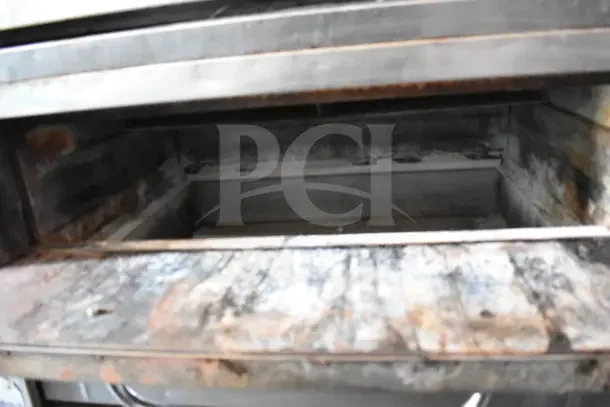 Two Bakers Pride commercial gas pizza ovens, single deck, shown on metal legs, used condition.