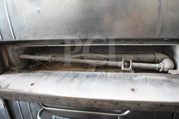 Bakers Pride commercial gas pizza oven interior, metal pipe labeled "Bakers Pride"; used condition, mounted on metal legs.