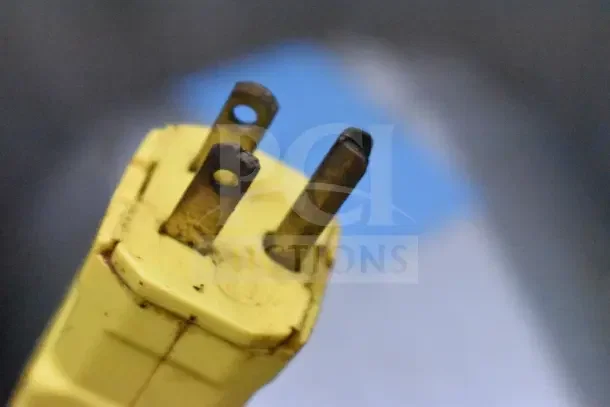 The image shows a close-up of a rusty, yellow electrical plug.