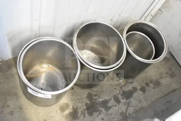 7 cylindrical metal drop-in bins, used condition, some wear visible. Ideal for storage or sorting. Auction lot includes all bins.
