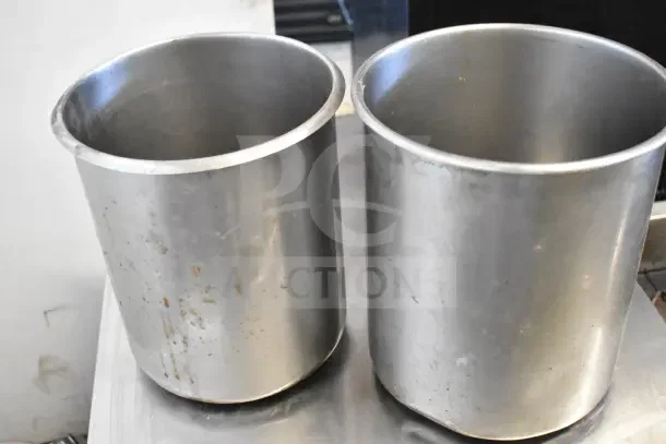 7 cylindrical drop-in bins, stainless steel, used condition with visible wear. Auction lot includes seven bins.