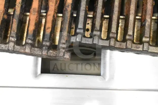 Commercial countertop gas charbroiler grill with metal grates. Visible signs of use; ideal for high-volume cooking.