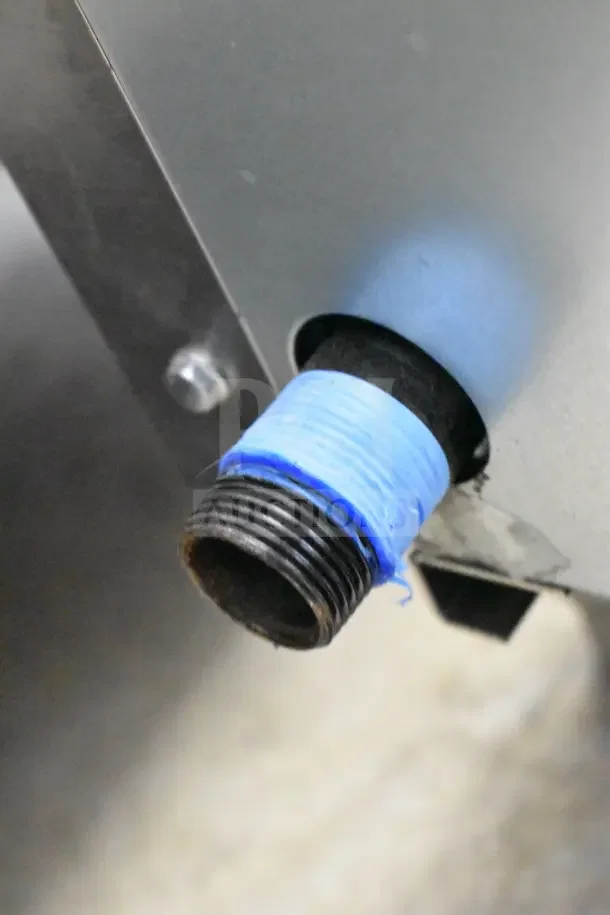 Commercial gas-powered charbroiler grill. Close-up of gas connector with blue tape, indicating secure fitting.
