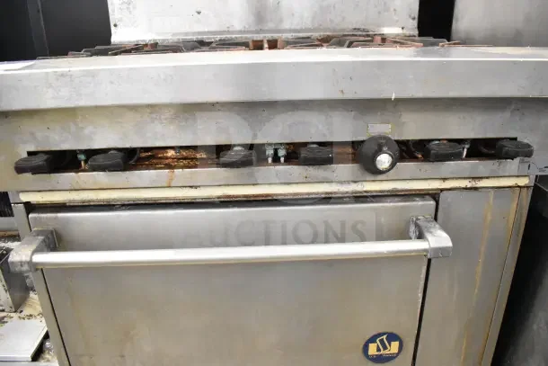 US Range commercial gas 6-burner range with oven, over shelf, and backsplash. Visible wear, on commercial casters.
