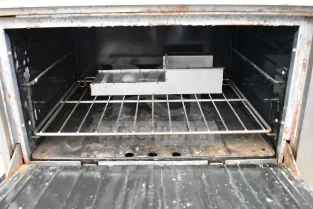 US Range commercial oven interior with metal rack and tray. Shows signs of wear. Suitable for professional kitchens.