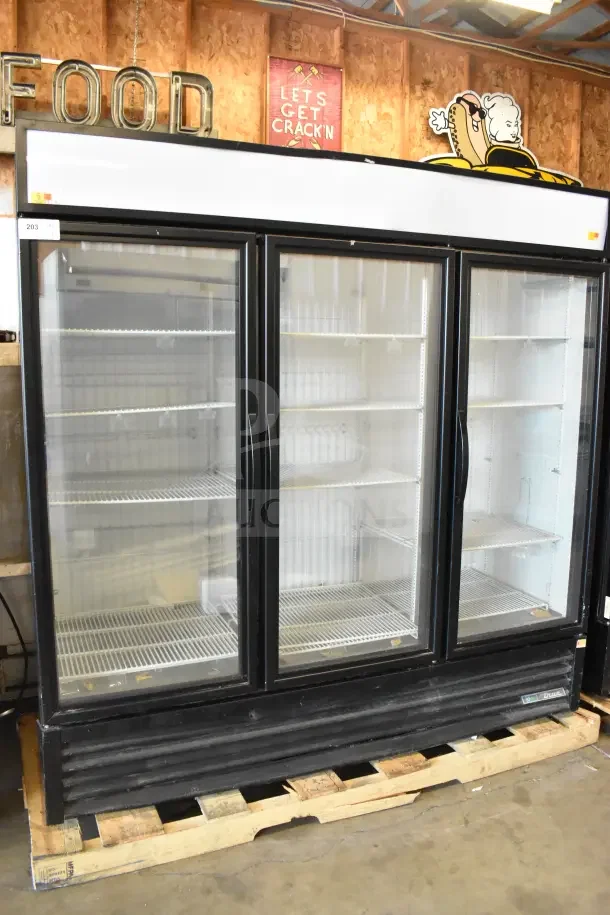 2018 True GDM-72F-HC commercial 3-door freezer merchandiser, black frame, glass doors, shelving, on wooden pallet.