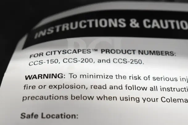 Close-up of Coleman CCS-200 fire pit manual showing instructions and warnings for safe use.
