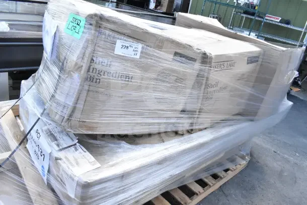 Brand new lot of scratch and dent items, including ingredient bins and work table, wrapped on a pallet. Labels visible.