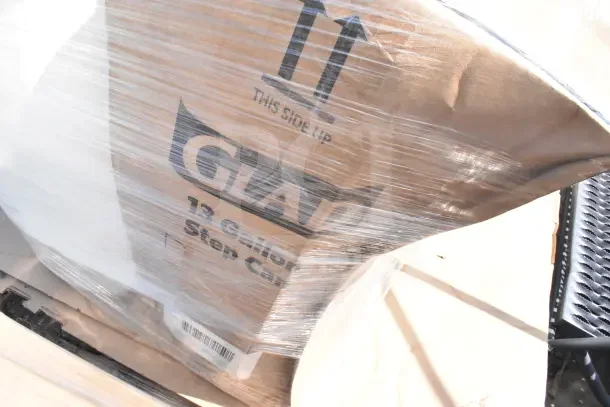 6 scratch and dent items wrapped, including Glad 13-gallon step can box visible through plastic. New, various kitchen items.