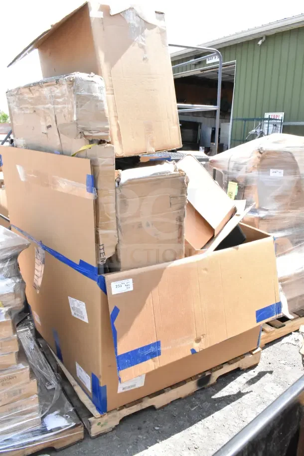 Stack of new scratch and dent items in boxes on a pallet, including a stool, sink, and trash can, with visible packing tape.