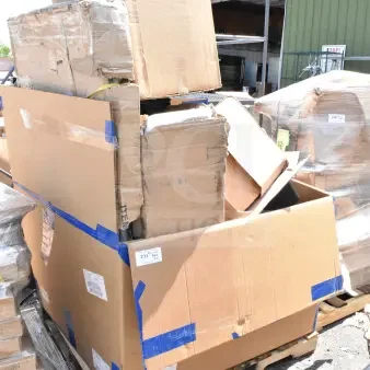 Stack of new scratch and dent items in boxes on a pallet, including a stool, sink, and trash can, with visible packing tape.