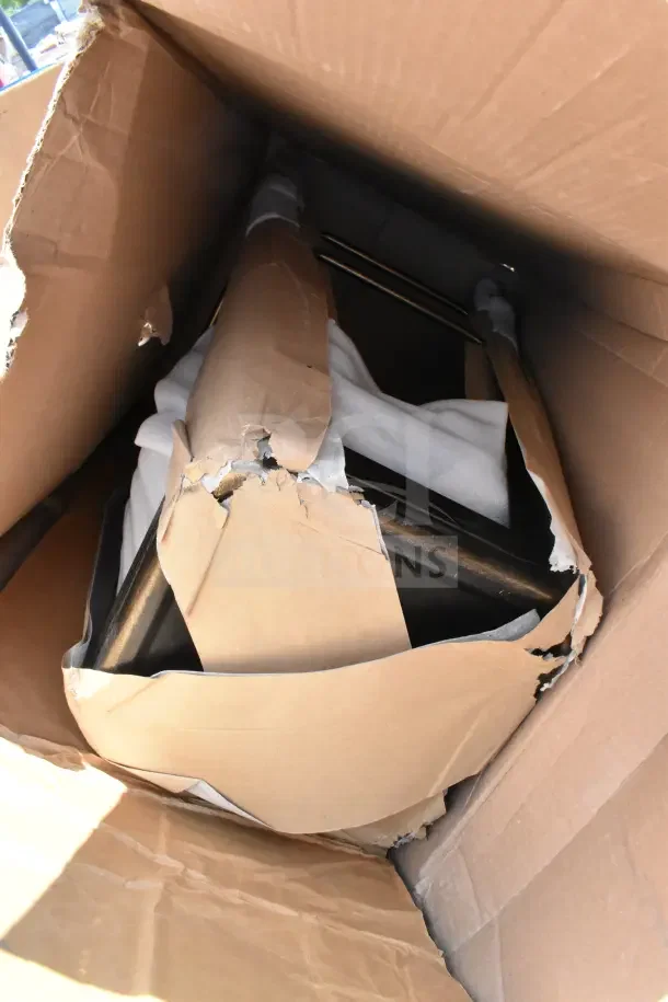 Cardboard box with new items showing minor damage, including a stool, sink, and trash can. Items are in scratch and dent condition.