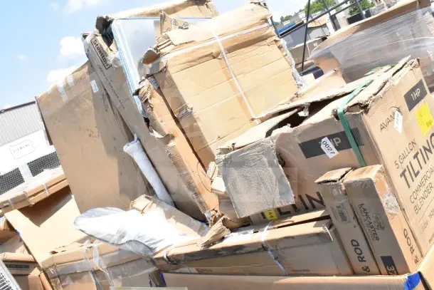 Stack of 12 new scratch and dent items, including AvaMix tilting blender boxes, showing visible wear and damage.