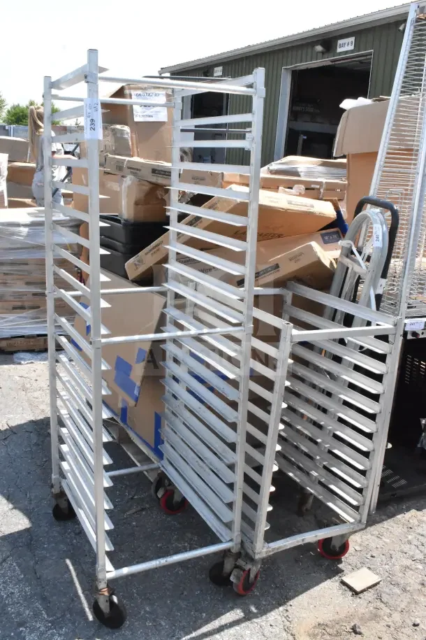 Two commercial pan transport racks with multiple shelves, metal construction, on wheels, in used condition.