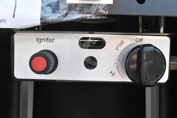 Floor-style propane gas heater controls with igniter button and temperature dial, showing off, pilot, and high settings.