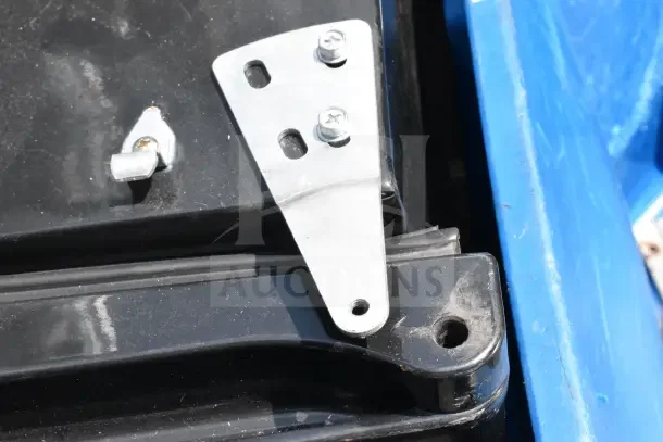 Metal bracket attached to a black and blue surface, possibly part of a mini cooler assembly.