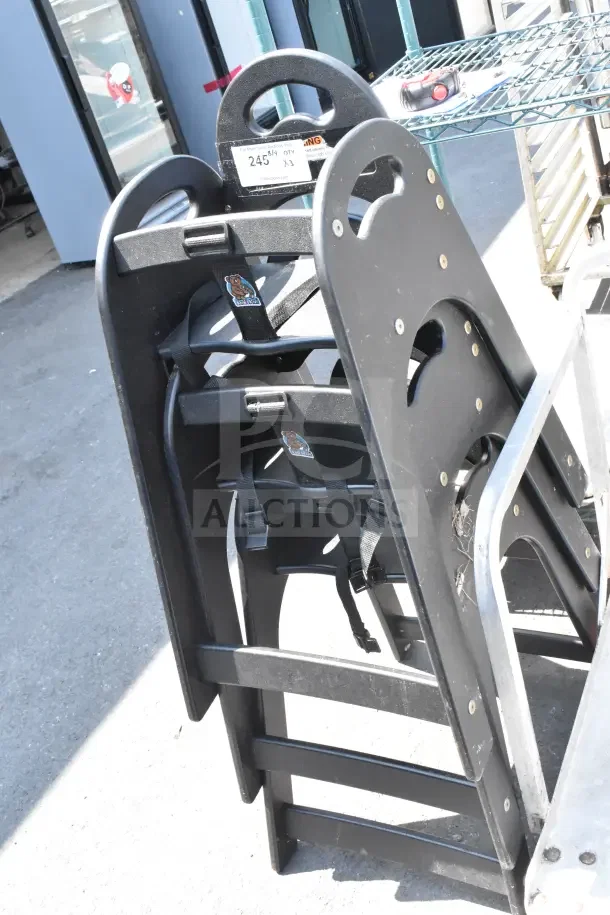 Three black Koala Kare high chairs, stacked. Visible safety straps and Koala Kare logo. Auction for three chairs.