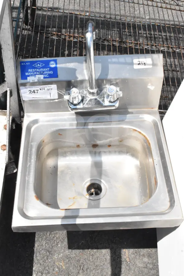 Commercial single bay wall mount sink with faucet and handles. Stainless steel, visible labels; rust and wear present.