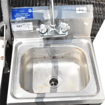 Commercial single bay wall mount sink with faucet and handles. Stainless steel, visible labels; rust and wear present.