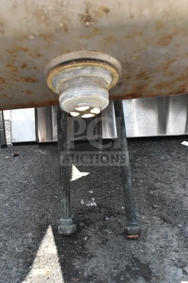 Commercial single bay wall mount sink with faucet and handles. Visible under-structure, moderate rust. Ideal for industrial use.