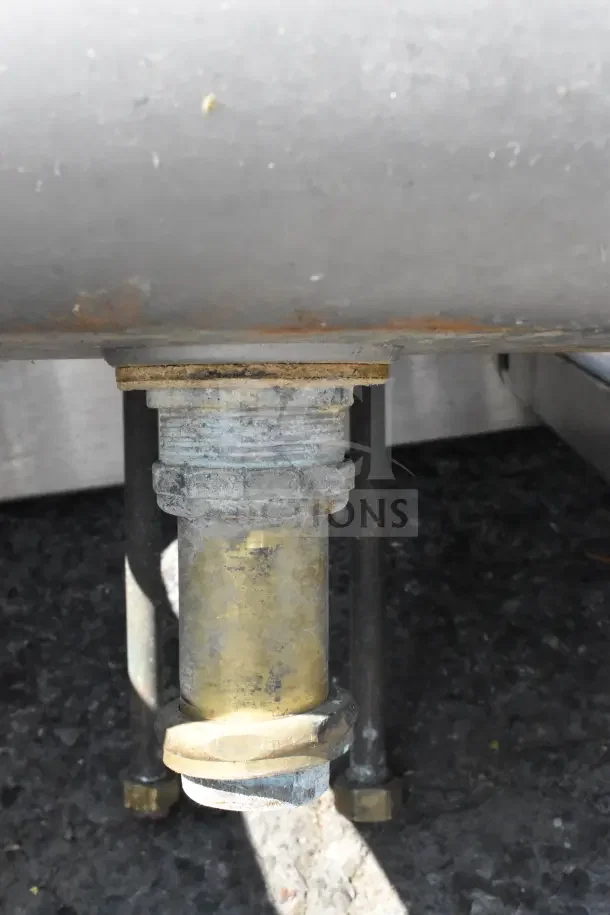 Commercial single bay wall mount sink underside showing drain pipe connection and mounting hardware, in used condition.