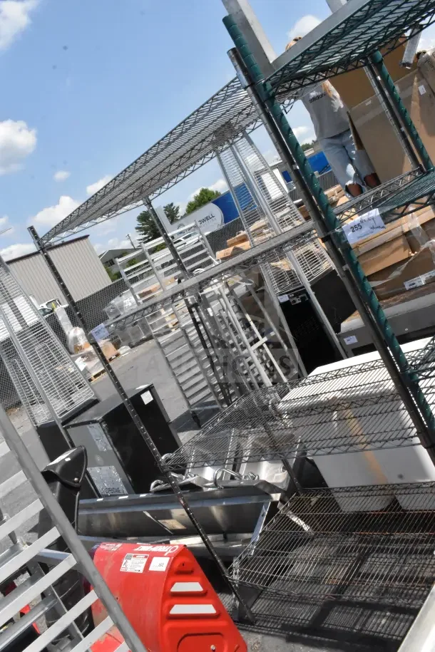 Chrome finish 4-tier wire shelving unit, disassemblable, outdoor setting, visible wear. Buyer dismantling required.
