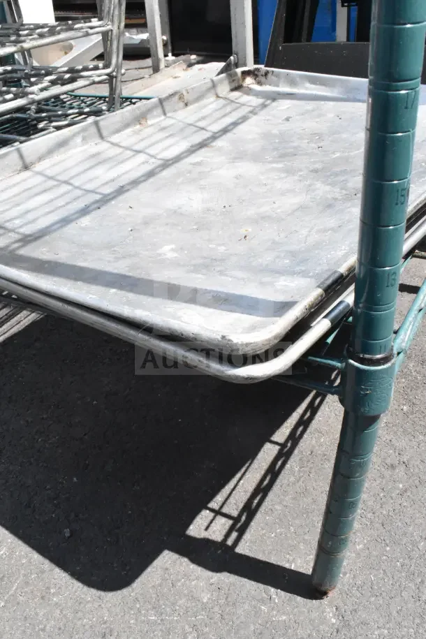 Green finish 4-tier wire shelving unit with baking pans and dunnage rack. Visible wear, dismantling required by buyer.
