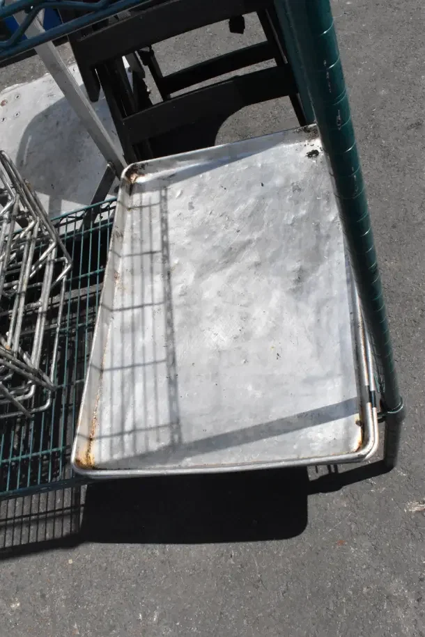 Green 4-tier wire shelving unit with baking pans, includes dunnage rack. Buyer must dismantle for shipping.