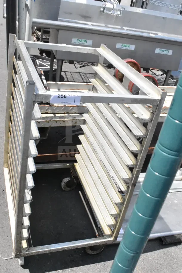Commercial pan transport rack with multiple slots, sturdy metal construction, on durable casters, moderate wear.