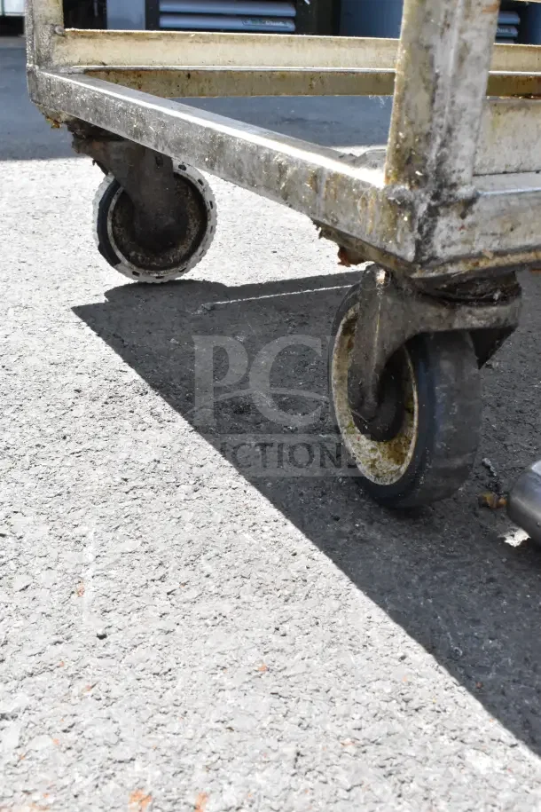 Commercial pan transport rack on commercial casters, showing signs of wear with visible rust and dirt.