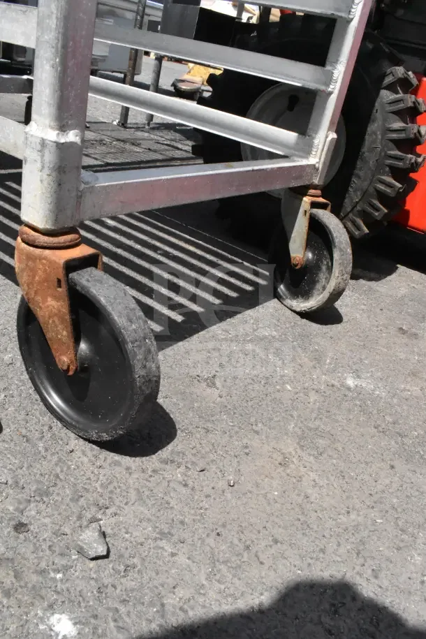 Newage Commercial Pan Transport Rack with durable commercial casters, metal frame, and visible minor rust on wheels.