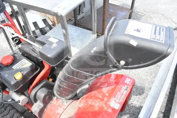 Troy Bilt Storm 2620 Snow Blower with red and black finish, visible controls, and chute. Signs of use, model label prominent.