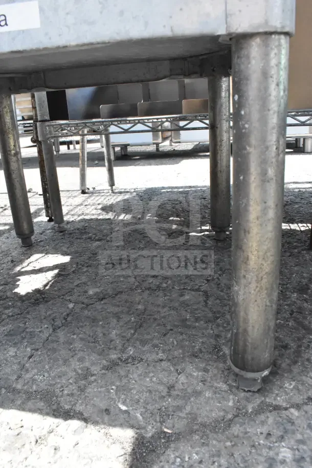 Commercial metal table with under shelf, durable legs, and visible wear, ideal for industrial use or kitchen settings.
