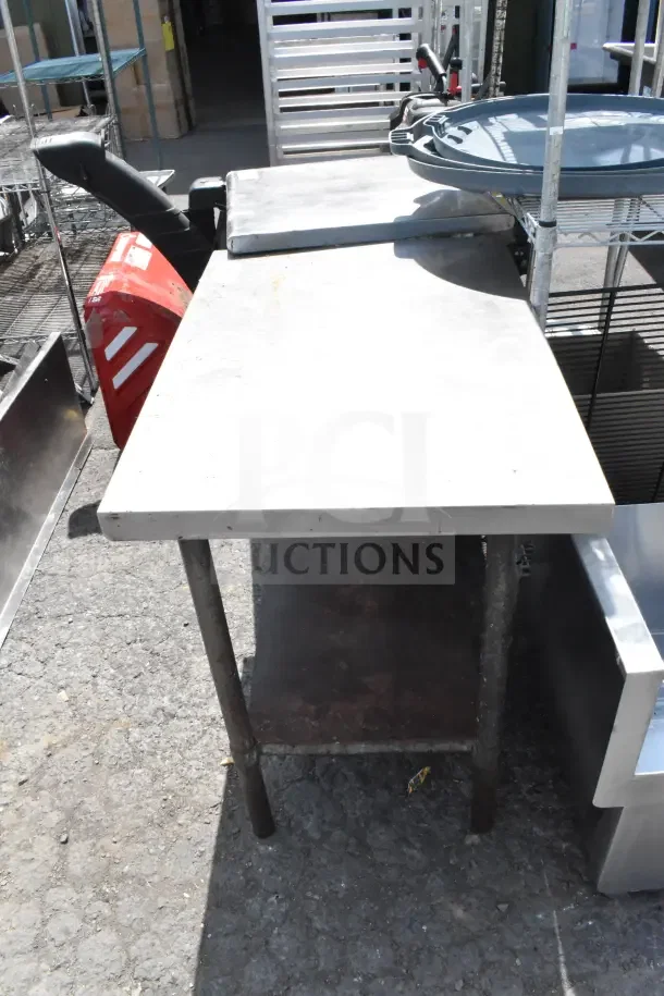 Commercial table with under shelf, metal frame, weathered condition, ideal for industrial use. Features sturdy legs and spacious surface.