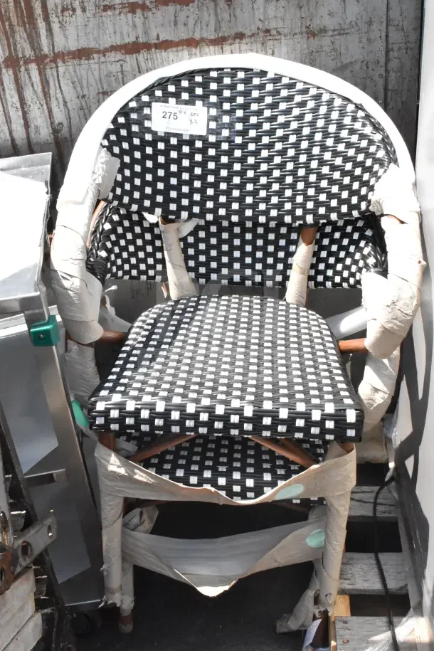Black and white woven armchair, brand new, with protective wrapping. "275" price tag visible. Scratch and dent condition.