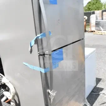 Stainless steel reach-in cooler with freezer, 115 volts, 1 phase. Minor scuffs, visible blue tape and sticker on door.