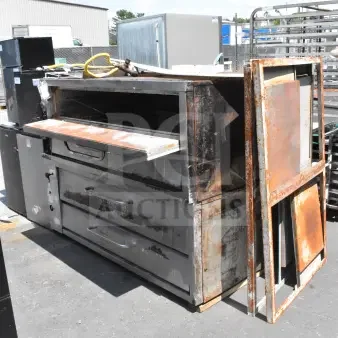 2 Bakers Pride commercial gas-powered single deck pizza ovens, weathered, outdoor setting. Handles intact, rust visible.